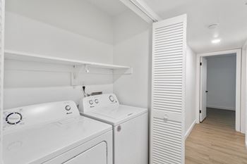 a washer and dryer in a white laundry room with a white closet
